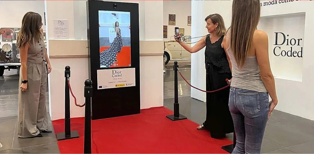 Visitantes frente al espejo virtual de pruebas de la exposición Dior Coded en el MAM de Málaga